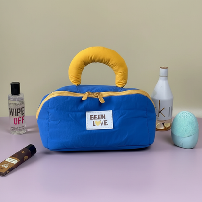 Royal blue quilted travel storage bag with yellow handle and zipper